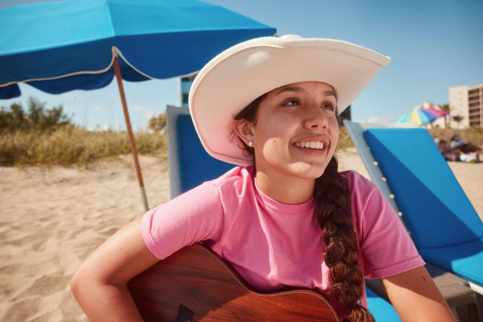 Girl with guitar on sunny beach.
