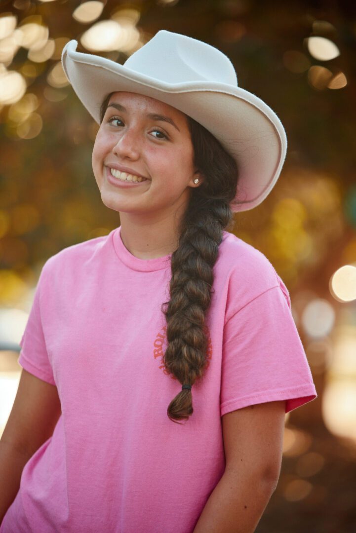 Smiling girl wearing a cowboy hat.