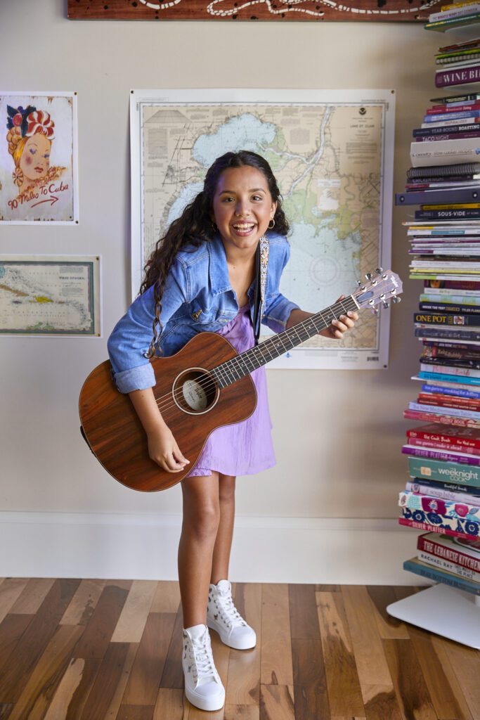 A girl holding a guitar in her room